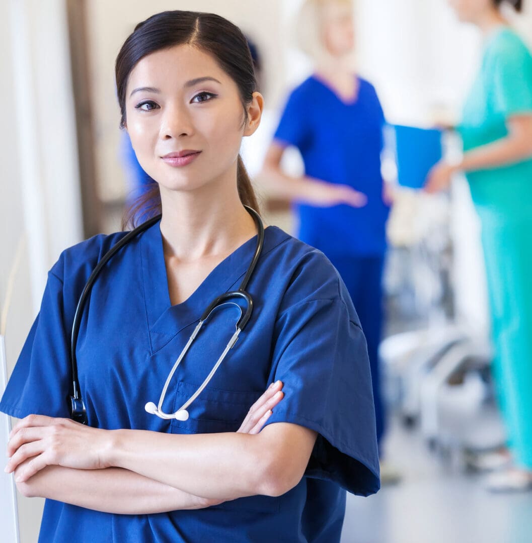 Portrait confident Asian Chinese female hospital clinical nurse wearing scrubs in corridor with medical center team